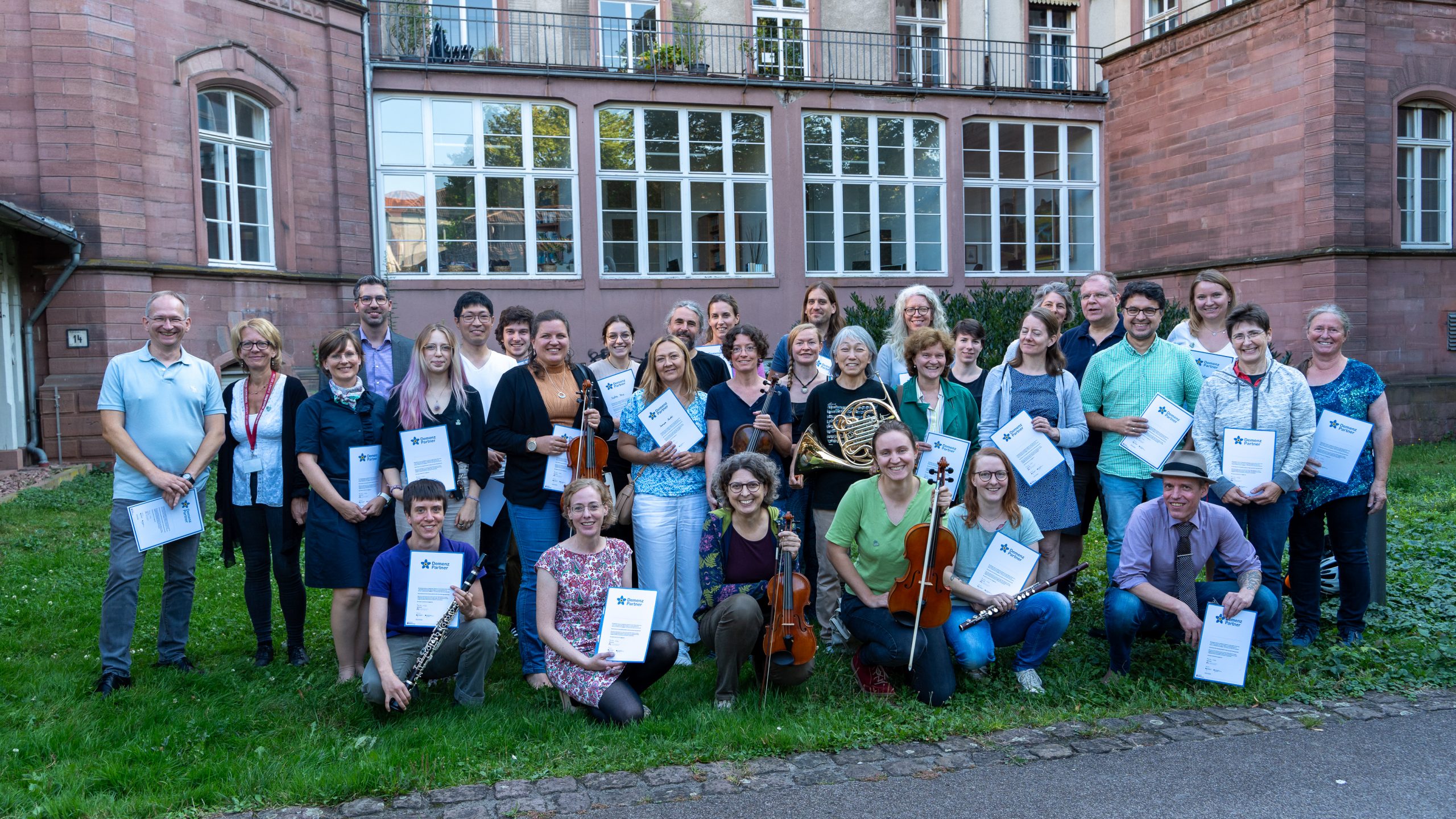 Die Mitglieder des Heidelberger Orchesters posieren mit Instrumenten und Zertifikaten der Schulung