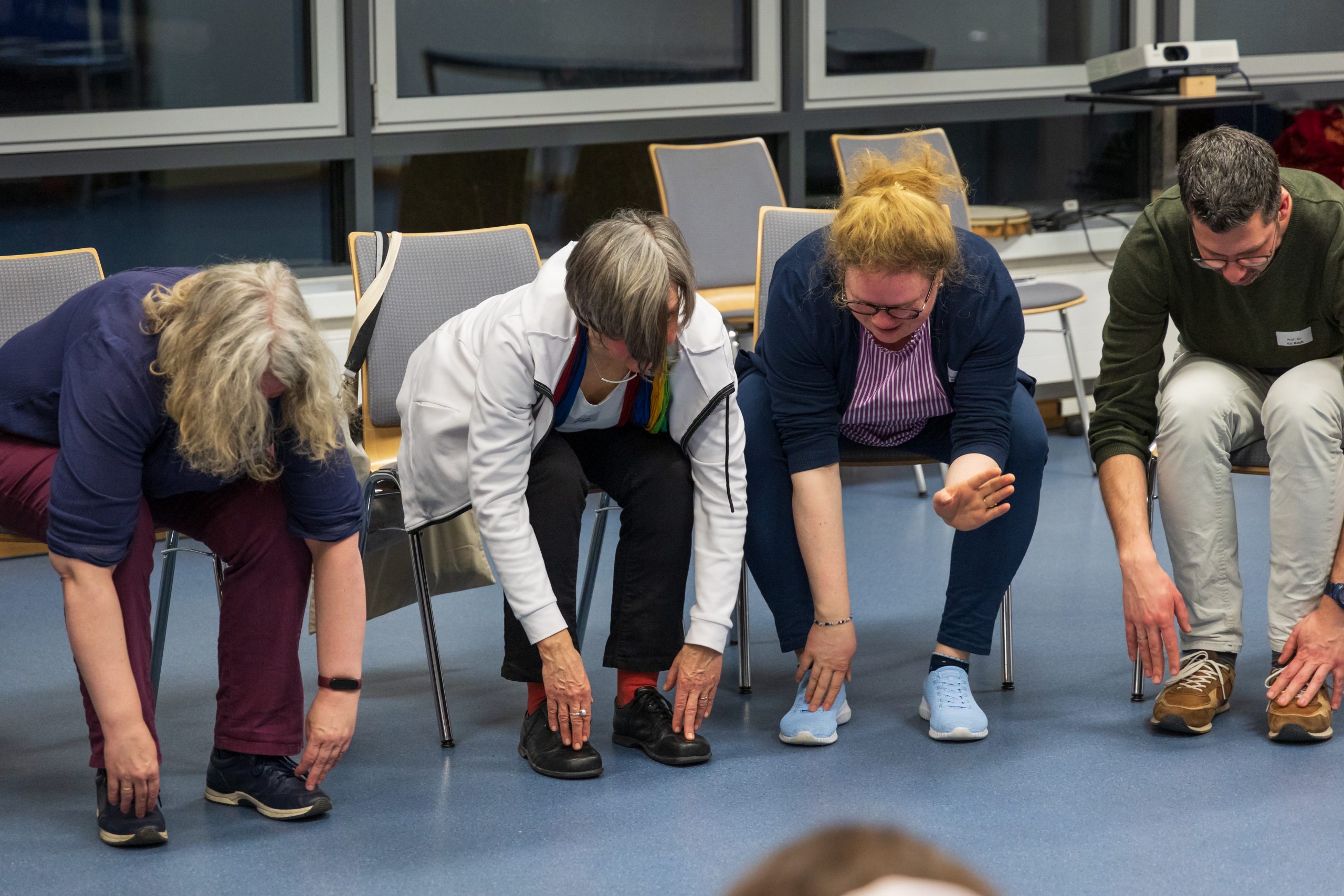 Mehrere Frauen tippen sich sitzend auf die Füße.