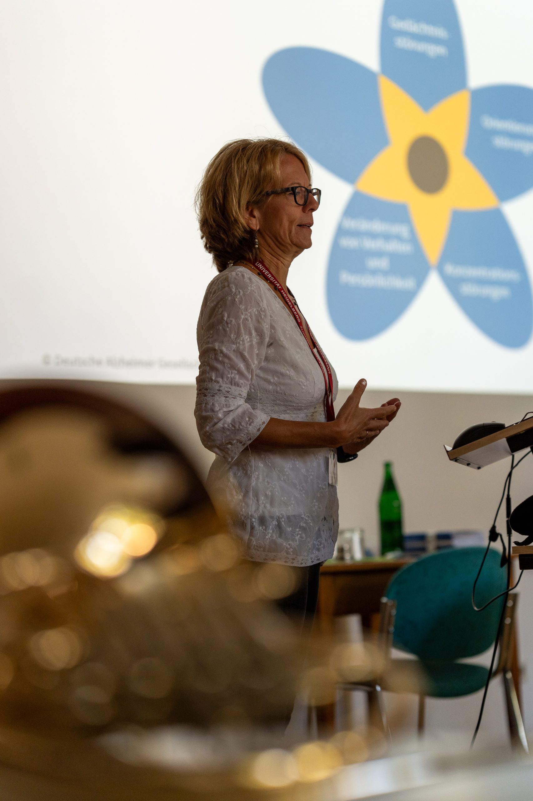 Frau steht sprechend vor einer Leinwand. Davor liegt unscharf ein Horn.