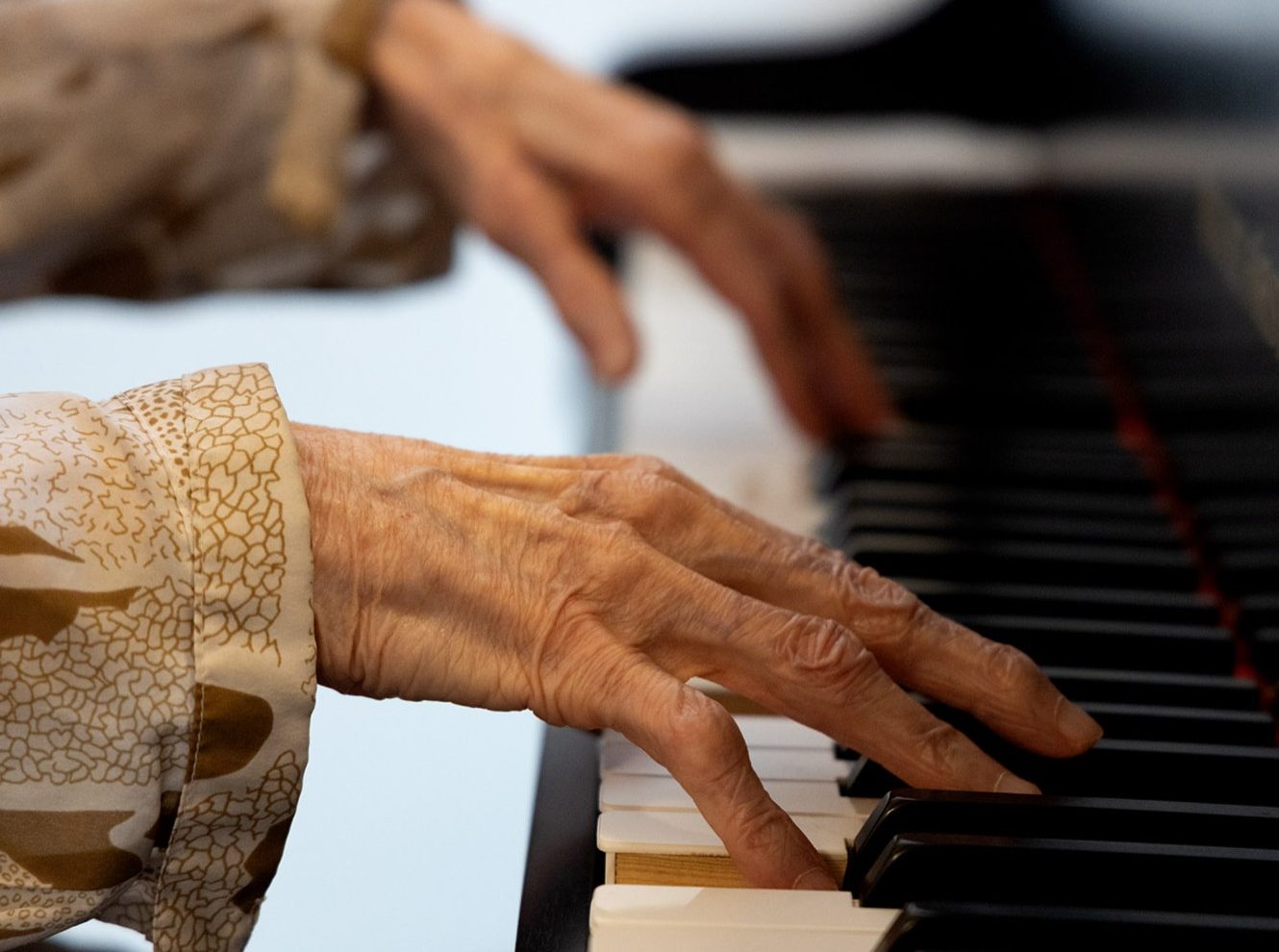 Die Hände einer Seniorin am Klavier.