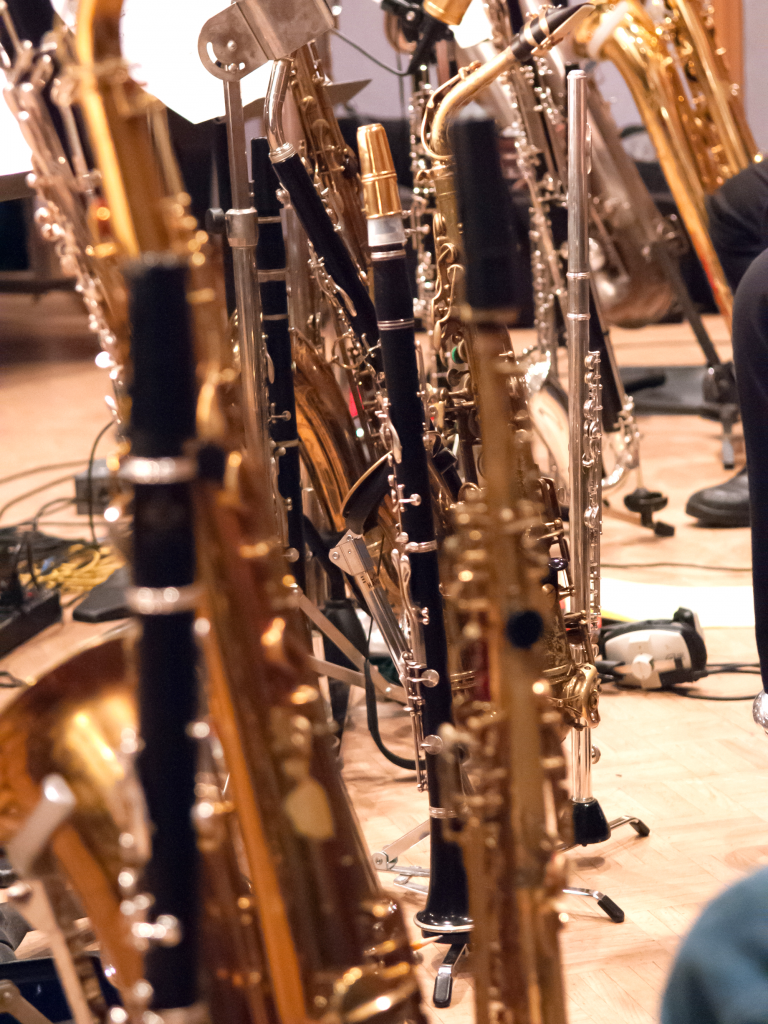 Holz- und Blechblasintrumente stehen aufgereiht nebeneinander. 