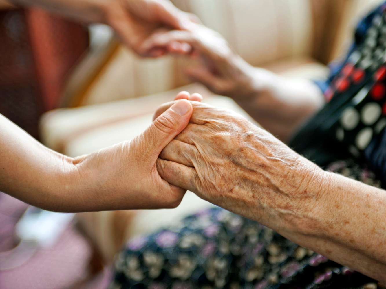 Eine junge Person und eine alte Person reichen sich die Hände.