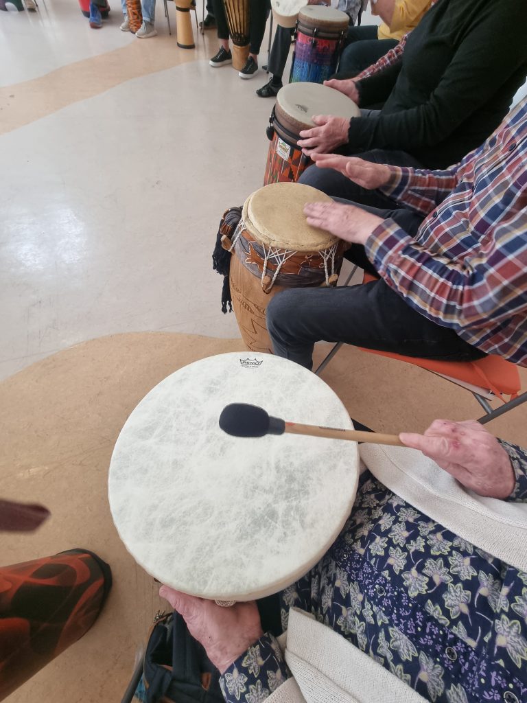 Hände von Senoir*innen, die im Kreissitzen und trommeln