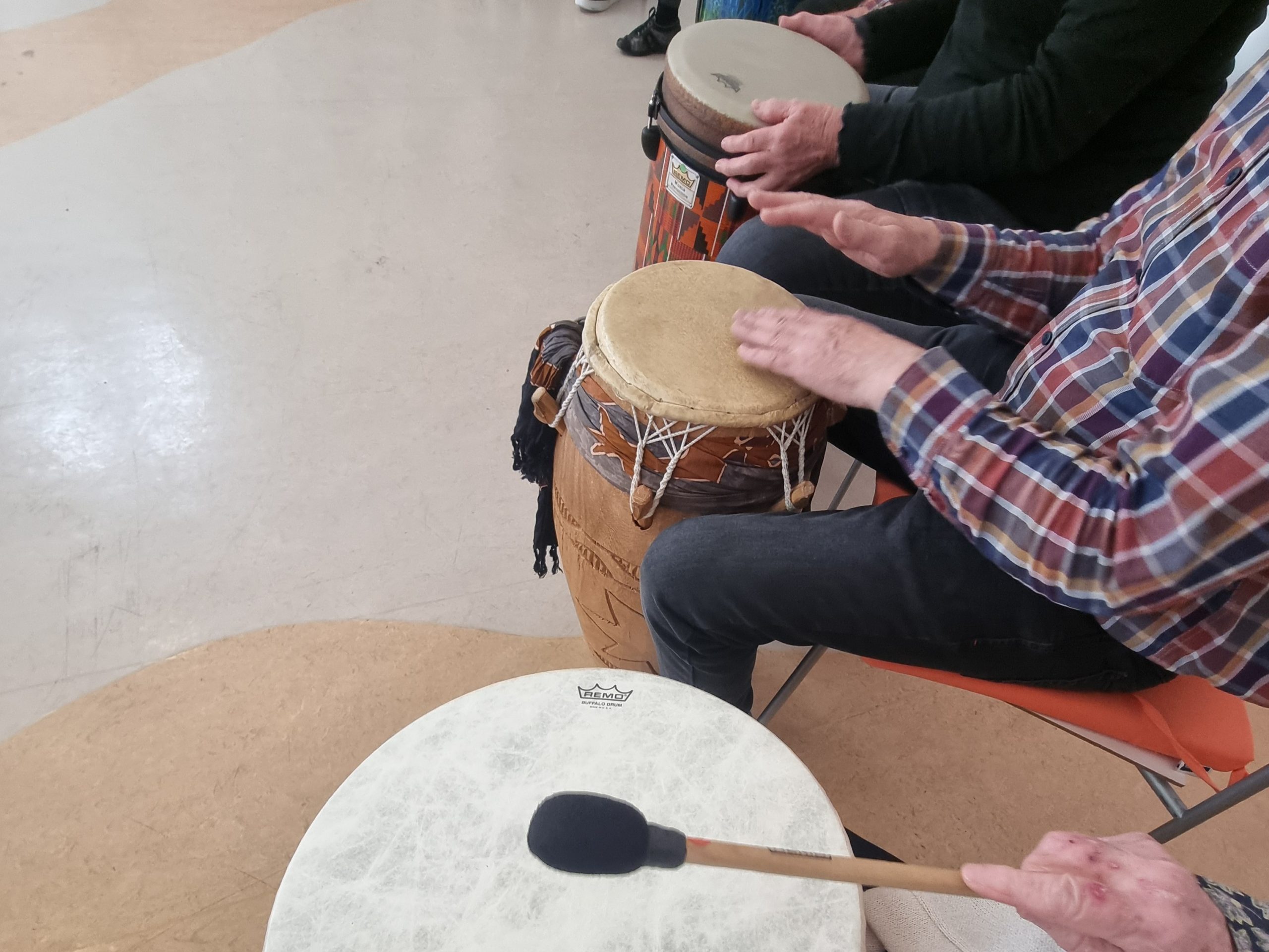 Hände von Senoir*innen, die im Kreissitzen und trommeln