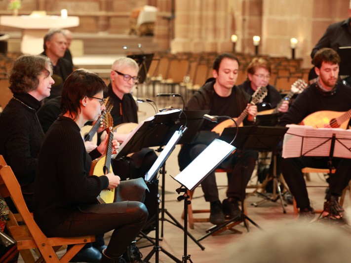 Zupforchester mit Mitgliedern aus vreschiedenen Generationen spielt in einer Kirche.