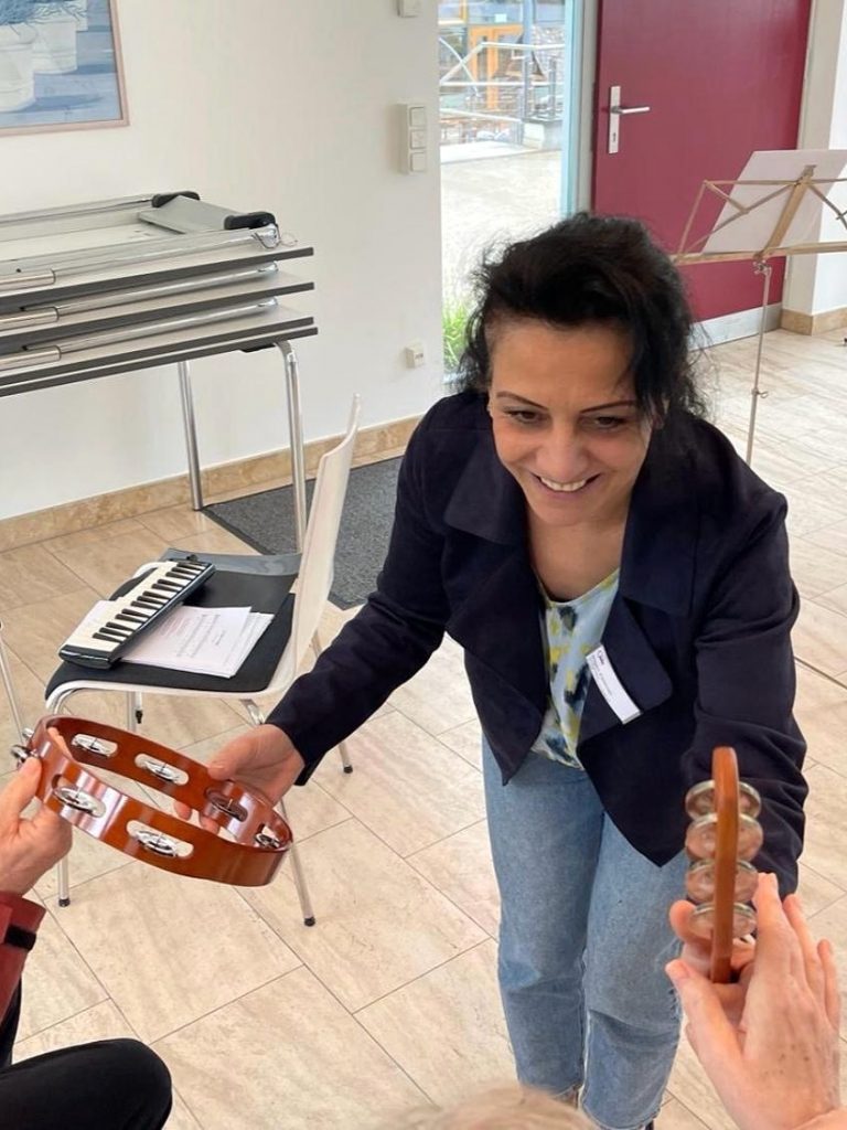 Die Porjektleitung reicht zwei Teilnehmenden Schellenkränze. 